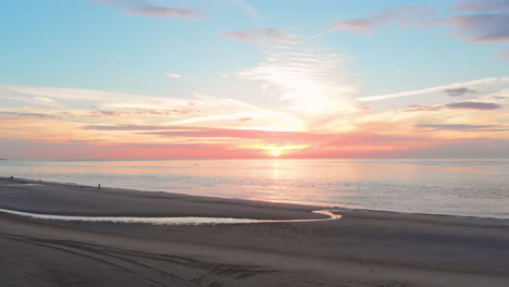 Una-Marea-Baja-Tranquila-En-La-Playa-Cerca-De-La-Barrera-De-Marejada-En-El-Suroeste-De-Los-Países-Bajos,-Durante-La-Puesta-De-Sol