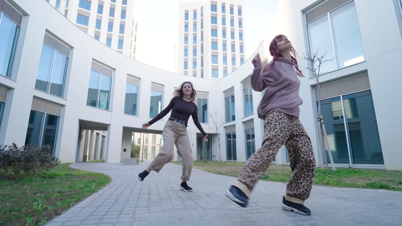 Young women dancing outside modern building