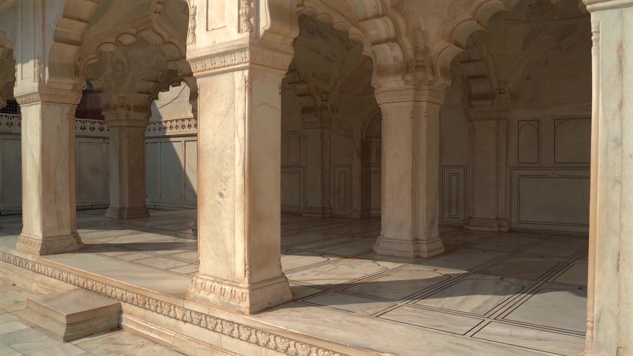 Ampia veduta di pilastri in marmo bianco, archi lobati e pavimento in pietra intarsiata di un padiglione reale al Forte di Agra in Uttar Pradesh, India