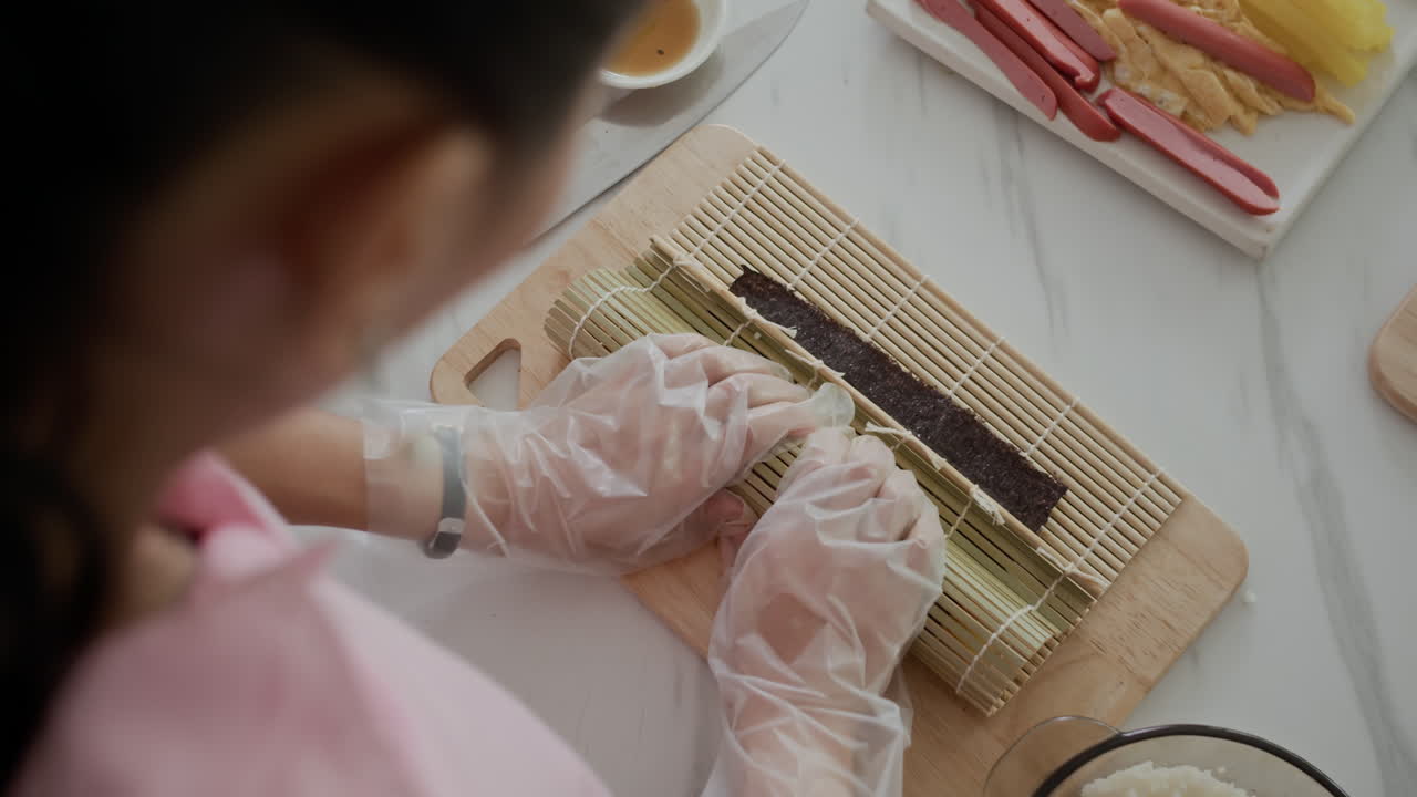 Girl Doing Kimbap Roll with Nori High Angle