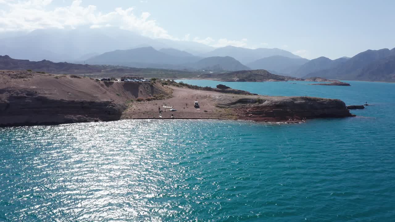 drone hacia un grupo de personas en la orilla del lago de agua azul turquesa