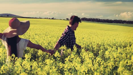 Romantic-couple-holding-colorful-balloons-and-running-in-mustard-field