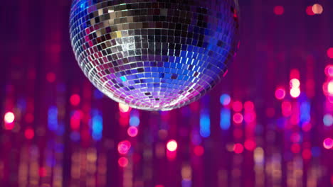 close up of mirrorball slowly revolving in night club or disco with sparkling lights in background 1