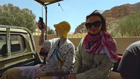 tourists taking pictures in a desert tour vehicle in wadi rum, jordan