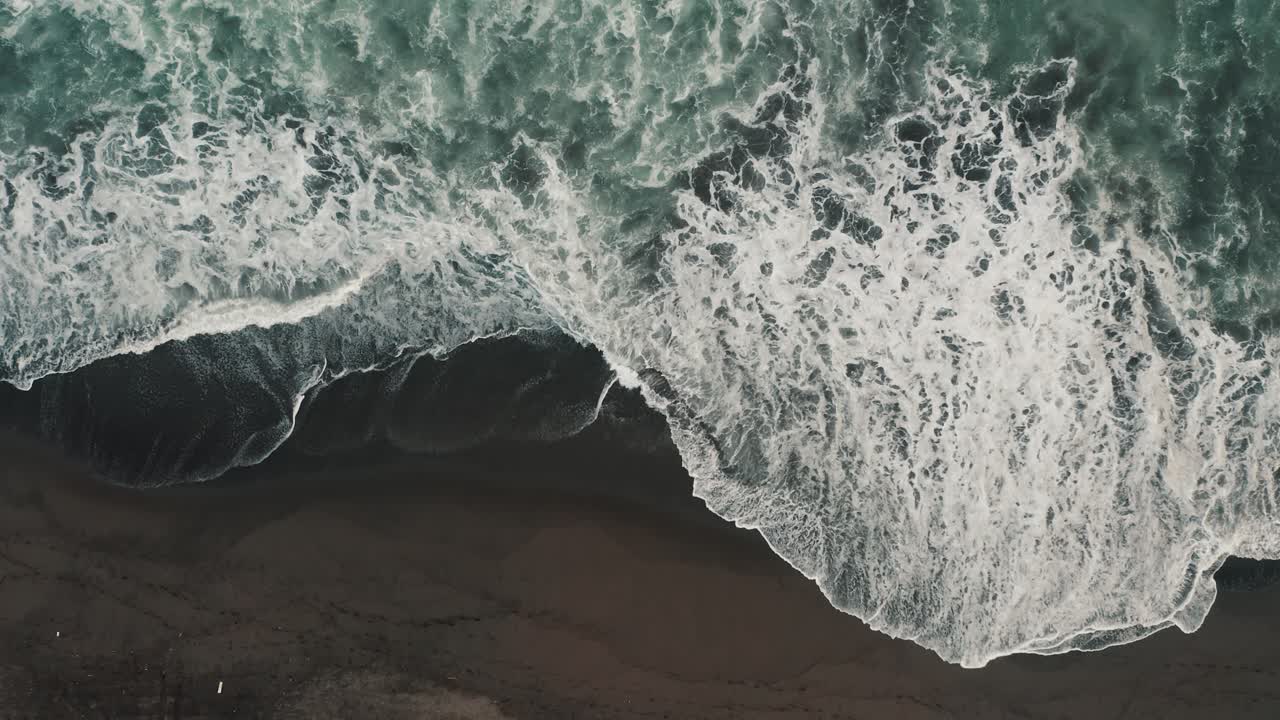 Ocean Waves With Foam Splashing On The Black Sand Beach Of El Paredon In Guatemala - aerial top down
