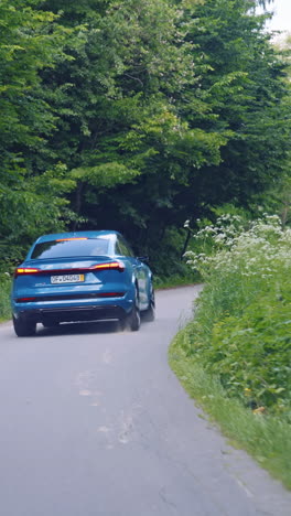modern urban car riding on road. modern electric car rides through in cold blue style. vertical video