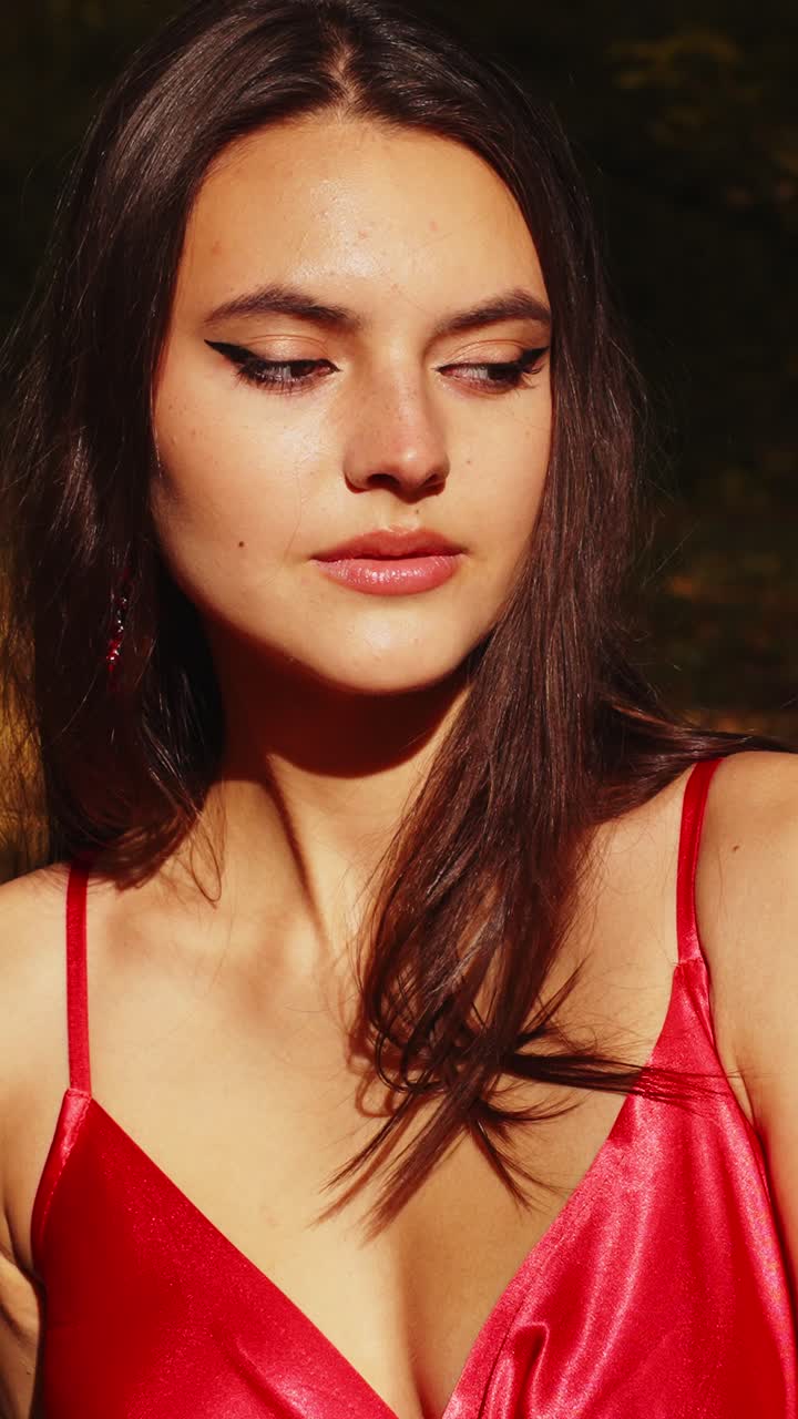 Elegant Portrait of a Woman in a Red Dress with Eye Makeup Against a Natural Background, Capturing Grace and Beauty in Soft Natural Light