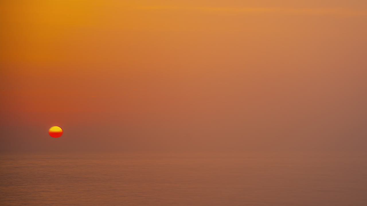 el sol se pone detrás del horizonte del mar brumoso, timelapse
