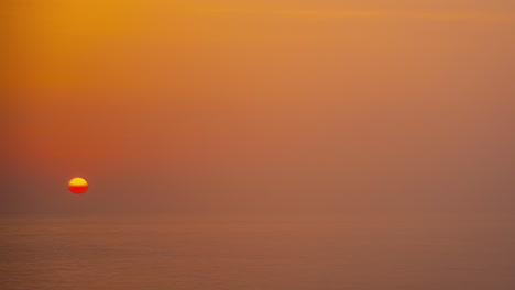 sun sets behind the foggy sea horizon, timelapse