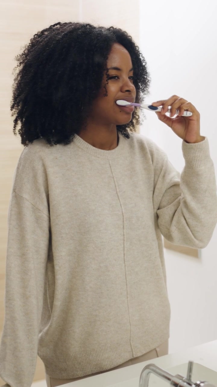 Giovane donna afroamericana felice che si lava i denti