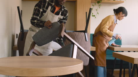 waitress and waiter cleaning coffee shop table with disinfectant spray and rag