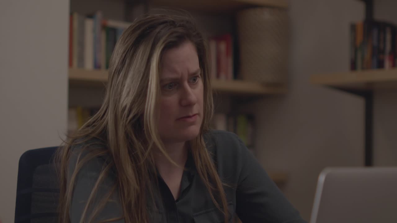 A professional at work speed typing quickly and aggressively on her laptop. She sits in a professional setting and types with intensity ahead of a deadline