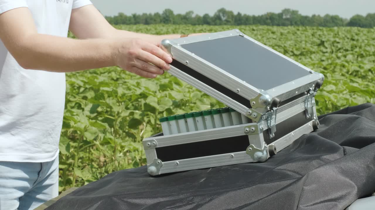 실험실 조교는 식물 분석을 위한 실험실 장비를 가진 케이스를 열었습니다.