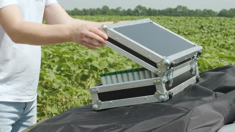 laboratory assistant opens a case with laboratory equipment for plant analysis