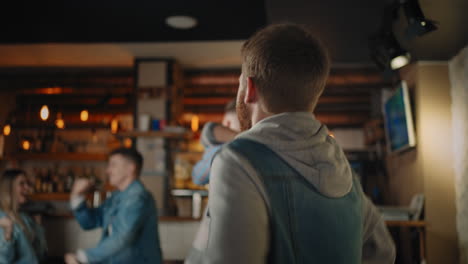 A-group-of-men-and-women-in-a-pub-cheering-for-their-national-team-at-the-World-Cup..-Fans-celebrate-a-goal-by-watching-TV-in-a-bar.-Basketball-hockey-baseball