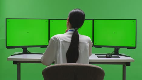 세 개의 모니터에서 일하는 여성 녹색 화면