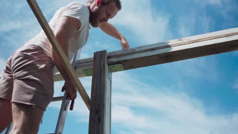 hombre en una escalera usando abrazaderas en estructuras de marco de madera