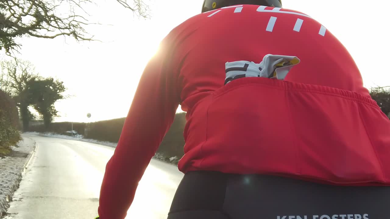 Slow motion cyclist cycling on road in snow during sunset sunrise 2