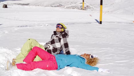 Couple-resting-on-hill-after-skiing