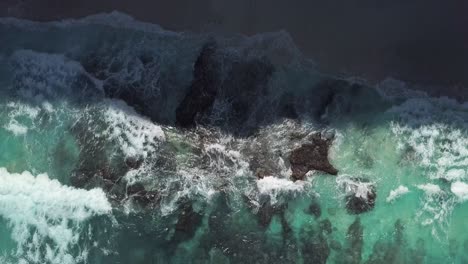 Aerial-view-of-the-waves-of-crystal-blue-water-hitting-the-shore-line-of-diamond-beach-in-Nusa-Penida,-Indonesia