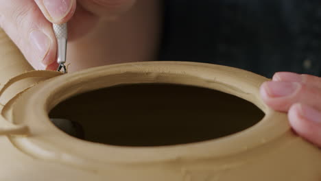 handheld close up shot of using a special tool for detailing in pottery