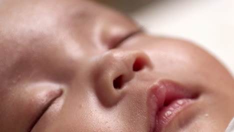 close-up shot of a newborn baby's face, showing its closed eyes, nose, and reddish lips