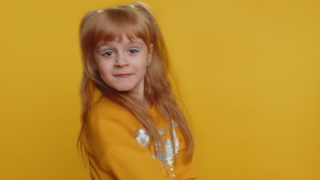 cute little girl in yellow sweater smiles and poses for a photoshoot