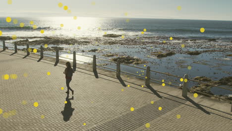 animation of yellow spots over biracial woman walking on promenade