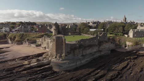 Aerial-drone-view-orbiting-the-shoreline-around-St-Andrews-Castle-in-Scotland,-UK