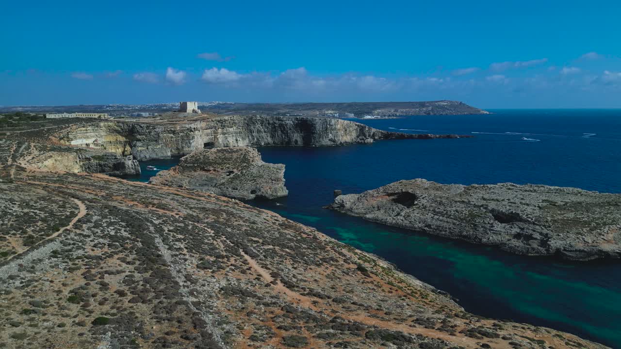 Drooni kuvaa Gozon rannikkomaisemaa, jossa on maaseutumaisia peltoja, kallioita ja tyyniä sinisiä Välimeren vesiä, Malta