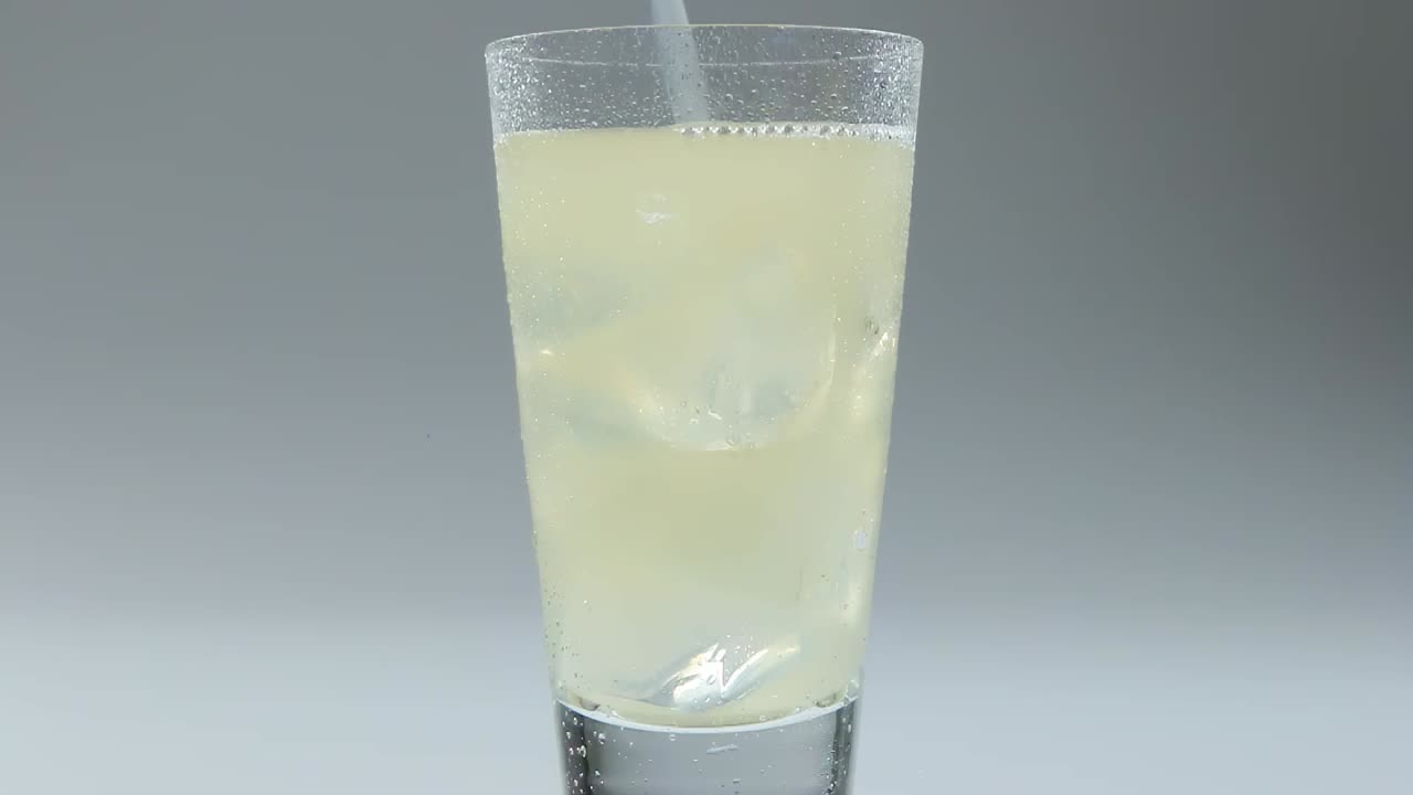 disparo fijo de bebida gaseosa que se vierte en un vaso transparente con hielo