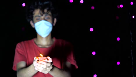 Young-man-celebrating-diwali-festival-with-medical-mask-and-diya