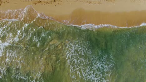 Drone-Con-Vista-De-Pájaro-Descendiendo-Sobre-Las-Olas-Del-Océano-Rompiendo-En-La-Playa-Hawaiana-De-Arena