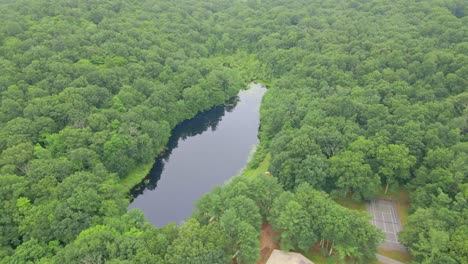 Flying-over-a-beautiful-pon-reservoir,-surrounded-by-trees-in-Ashford,-Connecticut