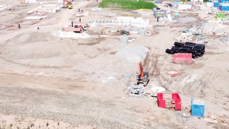 vehículo excavadora de excavación que prepara la vista aérea del tubo cilíndrico de hormigón en el sitio de construcción del desarrollo de viviendas