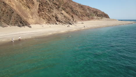 high fly by footage of fly fishing on a green emerald ocean beach at cabo san lucas, mexico