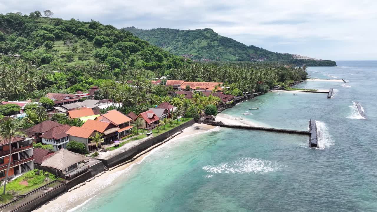 Hotels and resorts on beachfront at Candidasa Beach in Bali. Tropical landscape with palm trees.