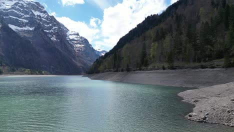 Blue-alpine-lake-with-behind-snow-capped-mountains