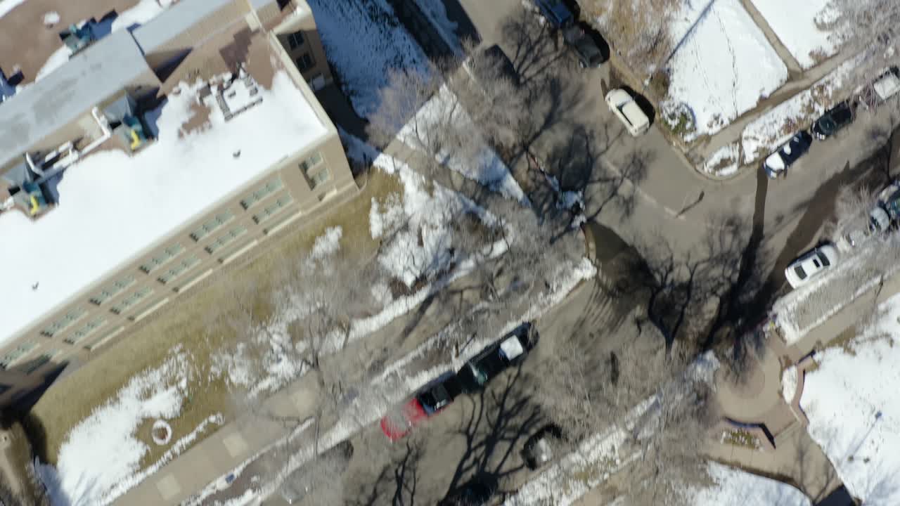 An aerial birds eye view drone shot from above a small town overlooking buildings and roads in the winter.