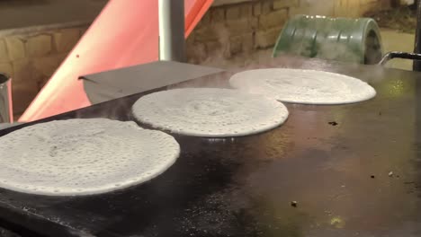 cooking dosa on skillet, street food in bengaluru, india. - closeup shot