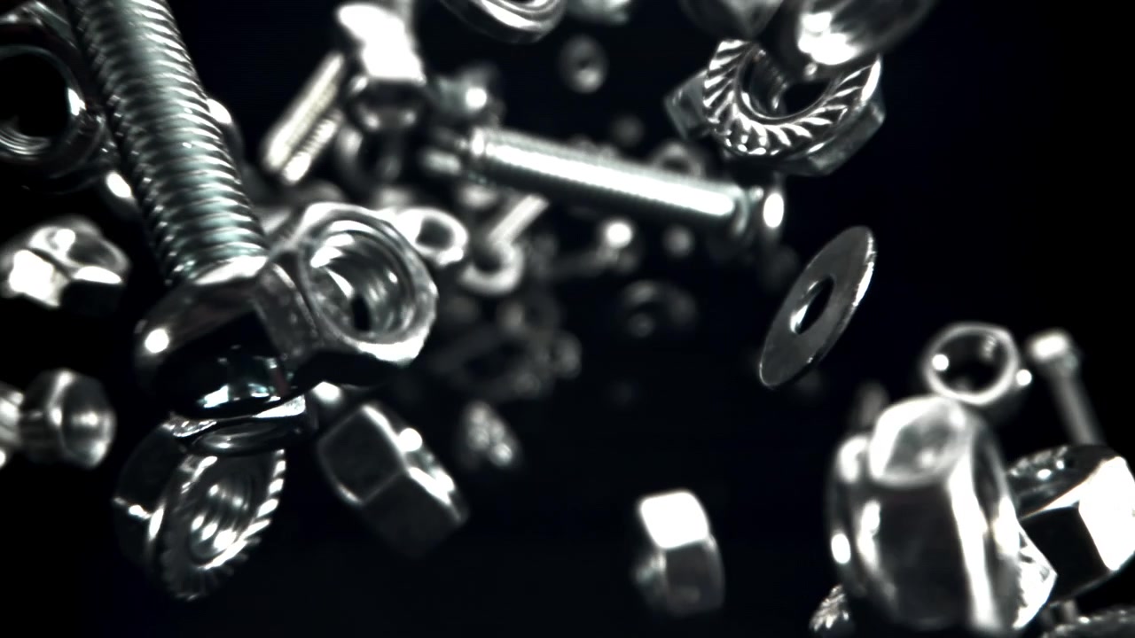 Glänsande metallmuttrar, bultar och brickor som svävar i slow motion