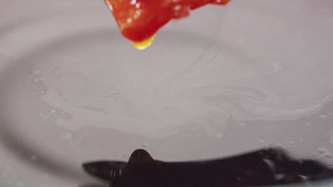 close up of red pepper slices in dark sauce with chopsticks