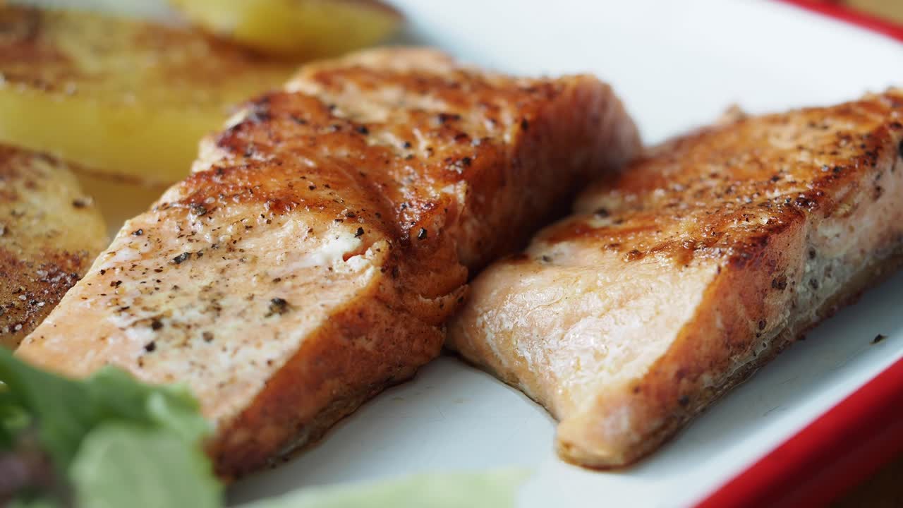 Nahaufnahme von gekochten Lachsfilets mit Kartoffeln und Grünem