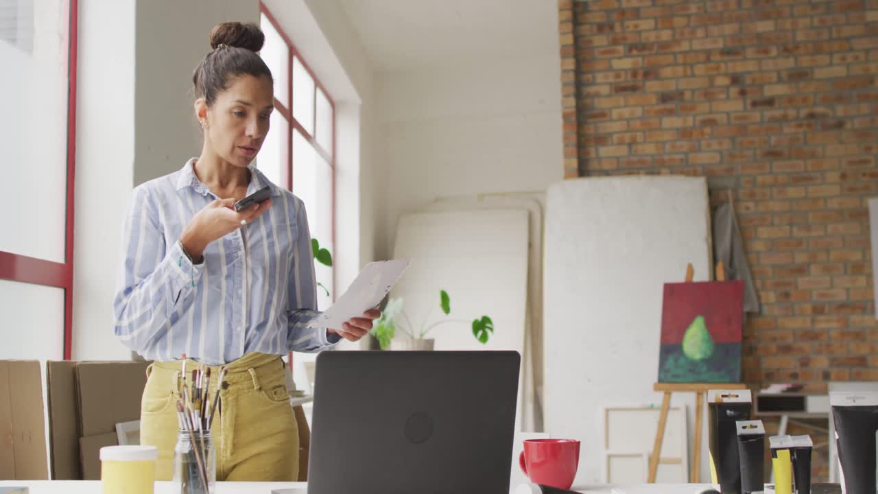 video di una designer bi-razziale che lavora su un laptop in studio