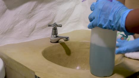 Housekeeping-clean-sink-bathroom-use-blue-gloves-for-Covid-19,-hygiene-concept-close-up