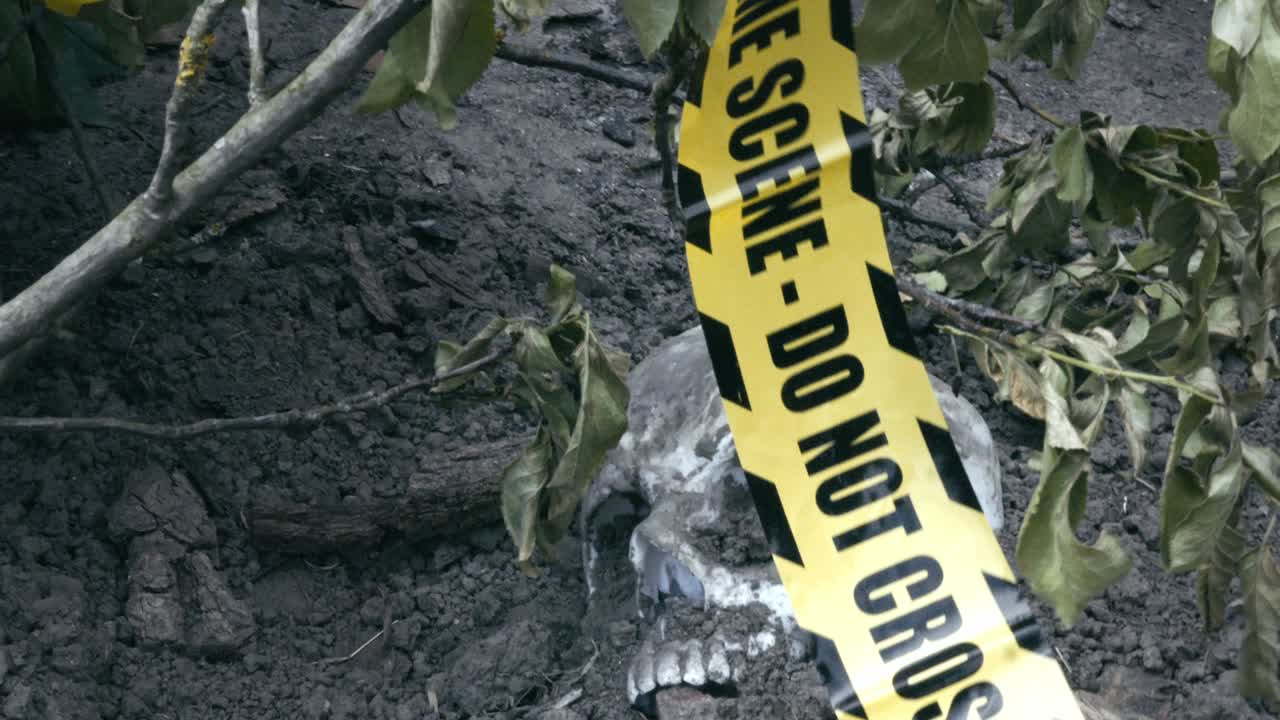 Police crime scene tape over macabre Human skull discovery in bushes
