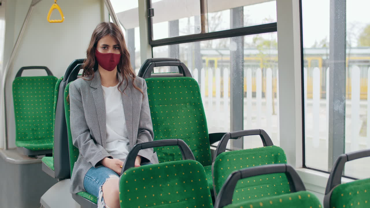 Young woman wearing a face mask sitting alone in public transport