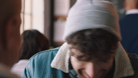 attractive-hipster-man-chatting-with-friend-drinking-coffee-in-cafe-laughing-enjoying-conversation-relaxing-in-restaurant