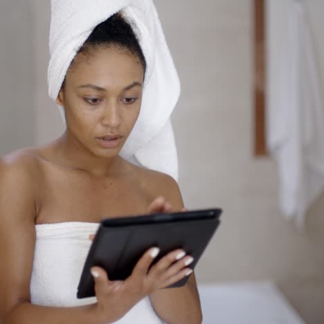 young woman wearing bath towel using tablet computer