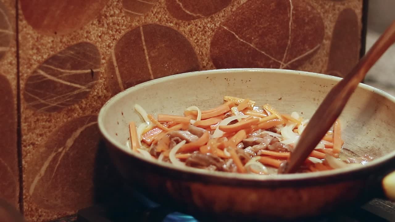 Stir frying strips of marinated pork with white onions, carrots and green chili in a pan, cooking stir fried flat rice noodles called Ho Fan